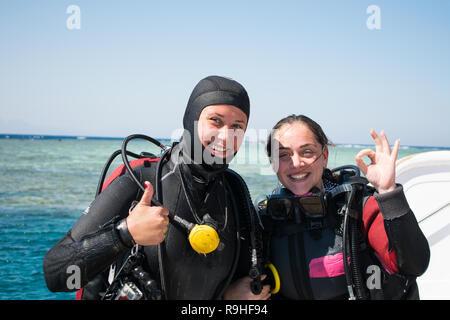 Zwei glückliche Taucher im Neoprenanzug und Masken mit Octopus in mouthes auf dem Hintergrund der azurblauen Meer OK angezeigt. Happy Girls in Neoprenanzüge. tauchen. Tauchen. Stockfoto