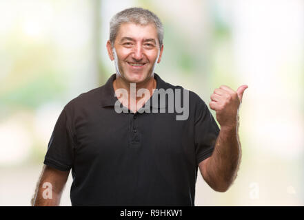 Gut aussehender älterer Mann über isolierte Hintergrund lächelnd mit glücklichen Gesicht und zeigt auf die Seite mit dem Daumen nach oben. Stockfoto