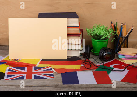 Sprachen lernen Konzept - leeres Papier, Flaggen, Bücher, Kopfhörer, Bleistifte auf hölzernen Hintergrund Stockfoto