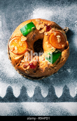 Nahaufnahme eines roscon de Reyes, drei Könige Kuchen auf epiphanie Tag gegessen Spanisch, auf einem grauen rustikalen Tisch Stockfoto