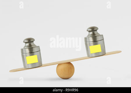 Gewichte mit leerem Papier Hinweis auf Balance Scale-Konzept des Ungleichgewichts Stockfoto