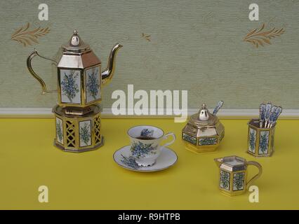 Englisch Teetasse, Untertasse, versilbert Teekanne auf eine silberne Vase Herd, Löffel und Teelöffel, creme Kanne, Sugar Bowl und sugarspoon, mit floralem Dekor Stockfoto