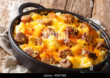 Traditionelle Auflauf von Kartoffeln, geräucherte Würstchen mit Käse Sauce close-up in einer Pfanne auf dem Tisch. Horizontale Stockfoto