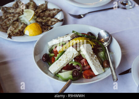 Kleinen gebratenen Fisch mit Zitrone und Griechischer Salat Stockfoto