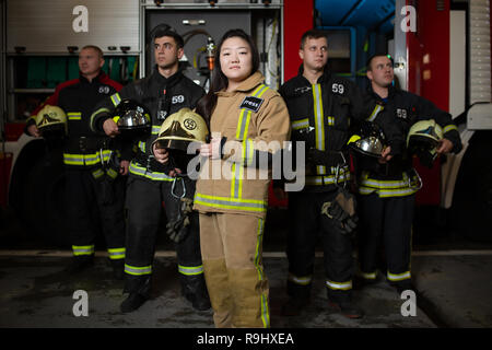 Bild von vier jungen männlichen und weiblichen Feuerwehrmänner auf dem Hintergrund der fire truck Stockfoto