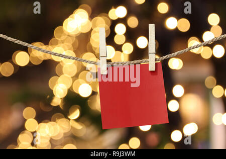 Leeres rotes Papier Notizen hängen auf wäscheleine für Design in Weihnachten auf Bokeh hellen Hintergrund, Notepad für Design Ideen für wichtiger Tag. Stockfoto