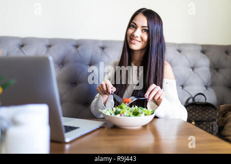 Junge Frau sitzend mit einem Laptop in ein Cafe und zum Frühstück Stockfoto