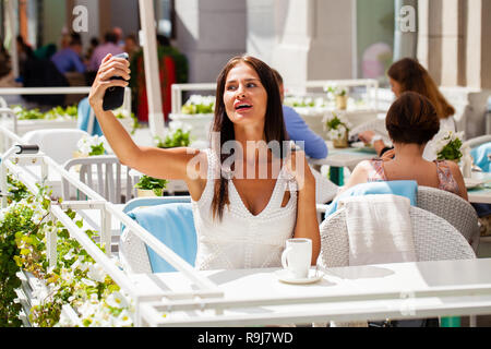 Schöne, Brünette Frau lächelnd nehmen Sie ein Bild von sich selbst mit einem Smartphone. Selfie, im freien Stockfoto