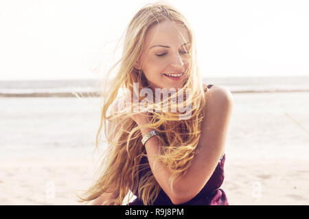 Glückliche junge Frau an einem windigen Tag am Strand Stockfoto