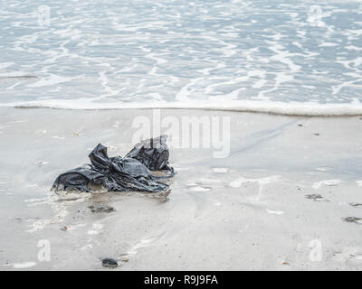 Kunststoff schwarz Müllbeutel gewaschen oben auf Ufer- und umweltschädliche Shoreline. Metapher Kunststoff Verschmutzung, Umweltverschmutzung, Krieg auf Kunststoff, plastik Müll Stockfoto