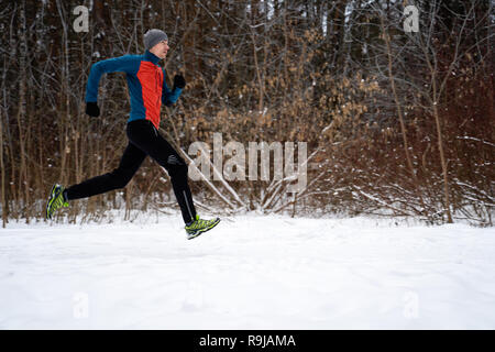 Bild von der Seite des Mannes in Sportkleidung, grauer Deckel auf Ausführen im Winter Stockfoto