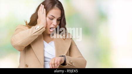 Schöne Übergrößen junge Frau tragen Winter Mantel über isolierte Hintergrund ein Blick auf die Uhr Zeit Sorgen, Angst, sich spät Stockfoto