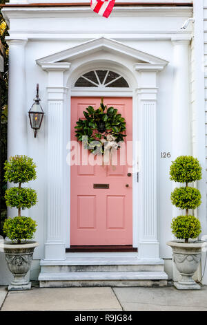 Traditionelle Magnolia Weihnachten Kranz ziert das rosa Holztür in das Dr Peter Fayssoux House Historic Home während der Feiertage auf Tradd Straße in Charleston, South Carolina. Fayssoux war der Surgeon General der Kontinentalarmee während der Amerikanischen Revolution. Stockfoto