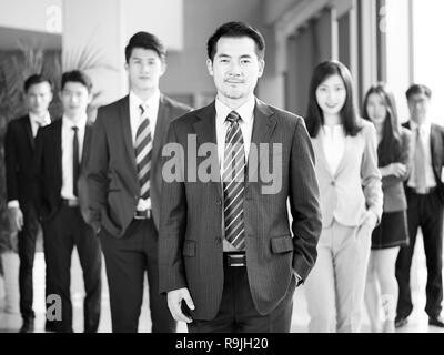 Porträt einer Mannschaft der Erfolgreichen asiatischen Unternehmer und Unternehmerinnen, von der Kamera suchen, Schwarz und Weiß. Stockfoto