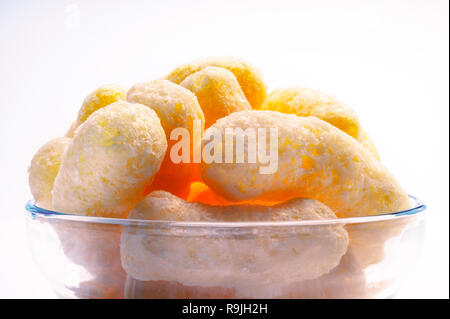 Gelber Mais Puffs in einer Glasschale. Crunchy aromatisiert aufgeblasen Snacks. Party, Film, TV, Game Snacks. Stockfoto