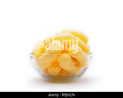 Gelber Mais Puffs in eine Glasschüssel isoliert auf weißem Hintergrund. Crunchy aromatisiert aufgeblasen Snacks. Party, Film, TV, Game Snacks. Stockfoto