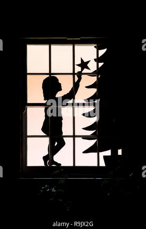 Festliche Weihnachten Haus Fenster anzuzeigen. Kind, einen Stern auf einen Weihnachtsbaum. Northamptonshire, England Stockfoto