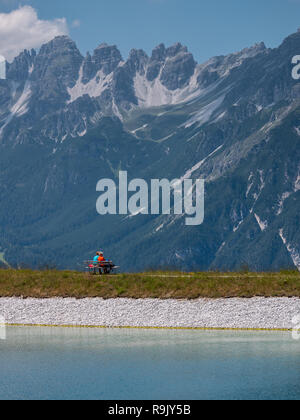 Ein paar der älteren Menschen ruht auf einer Bank in der Nähe der Bergstation der Seilbahn Serlesbahn Stockfoto