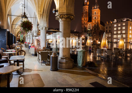 Café im Freien Tische in der Stadt Krakau in Polen bei Nacht, Blick von der Arcade der Coth Halle (Sukiennice) nach St. Maria Kirche am Hauptplatz in der Stockfoto