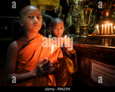 KYAING TONG, MYANMAR - ca. Dezember 2017: Mönche im Wat Jong Kham Kloster mit Kerzen in die Kamera schauen. Stockfoto