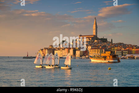 Blick auf die Stadt Rovinj in Kroatien. Segelboot Regatta im Hafen unter Golden Sun Light mit der Stadt im Hintergrund Stockfoto