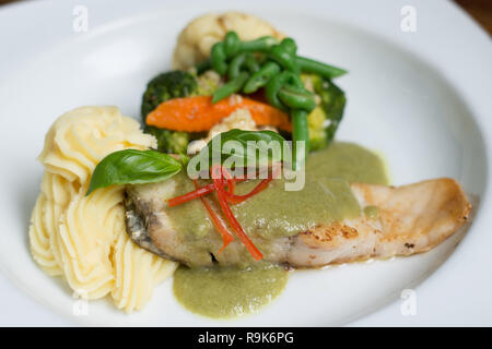 Frisches Filet vom Wolfsbarsch pan in Lemon caper Sauce mit Kartoffelpüree und grünen Gemüse gebraten Stockfoto