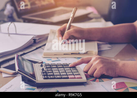 Business Konzeption: Nahaufnahme, Frau, Hand mit Taschenrechner und schreiben Sie mit am Büro Schreibtisch berechnen. Stockfoto