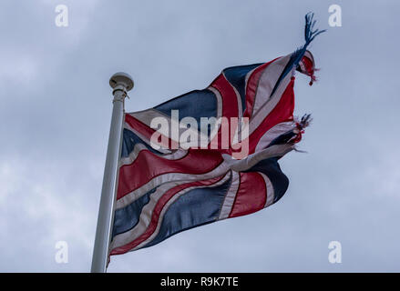 Ein schäbig und zerschlagen Union Jack Flagge oder Fahne fliegen von einem Fahnenmast in England Großbritannien. Britische Flagge. Stockfoto