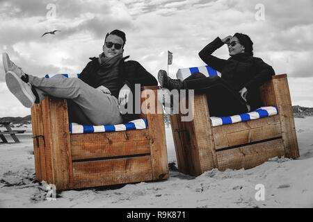 Junges Paar entspannende auf Sand Körbe am Strand des nördlichen Deutschland Insel Amrum. Stockfoto
