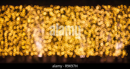 Glitzernde strahlende und funkelnde defokussierten Blinkende warmen Gold Licht (Bokeh) Beleuchtung outdoor Wand Dekoration Hintergrund. Besondere Feiertage, Festiva Stockfoto