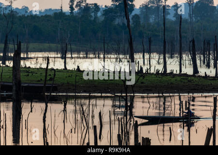 Thakhek, Laos - 19. April 2018: Boat Crossing eine atemberaubende Landschaft toter Bäume bei Sonnenuntergang in einem abgelegenen Gebiet von Laos gemacht Stockfoto