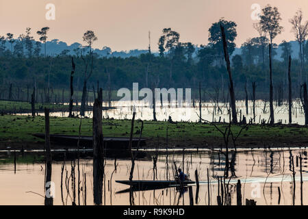 Thakhek, Laos - 19. April 2018: Boat Crossing eine atemberaubende Landschaft toter Bäume bei Sonnenuntergang in einem abgelegenen Gebiet von Laos gemacht Stockfoto