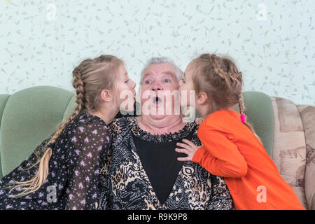 Enkelinnen kiss ihre Urgroßmutter Stockfoto