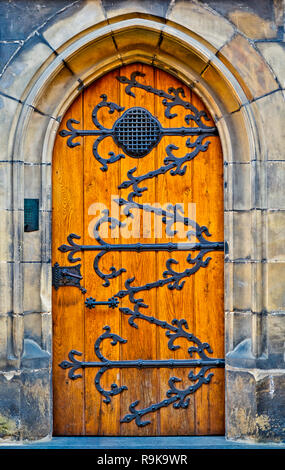 Hölzerne Tür des alten Typs mit Metall-Designs auf es geschlossen. Eingangstor einer Burg mit Steinmauer helle orange Ton. Konzept der Gelegenheit Schicksal Stockfoto