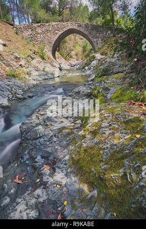 Mittelalterlichen venezianischen Brücke in die Schlucht zwischen den Felsen am sonnigen Frühling Abend. Zypern Brücke Elia. Stockfoto