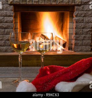Weihnachten. Gemütliche Szene vor dem gemütlichen Kamin mit zwei weißen Weingläser und Weihnachten Santa Claus hat. Stockfoto