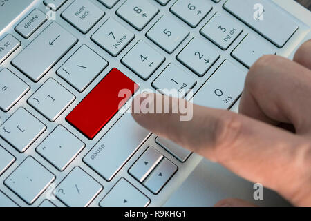 Hand die Taste drücken. Rote Taste auf Grau Silber Laptop Tastatur. Kopieren Sie Raum zu testen. Rote Taste. Ein männlicher Finger drückt eine Taste Farbe Grau Silber Stockfoto