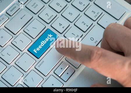 Computer Taste zeigt das Wort Feedback. Meldung auf der Tastatur drücken, einen männlichen Finger drückt eine Taste Farbe Grau Silber Tastatur eines modernen Laptop. Bu Stockfoto
