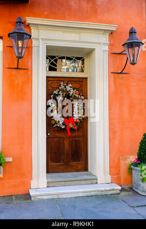 Traditionelle Baumwolle Weihnachten Kranz schmückt eine hölzerne Tür auf einem historischen Haus während der Ferien auf der Broad Street in Charleston, South Carolina. Stockfoto