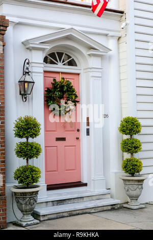 Traditionelle Magnolia Weihnachten Kranz ziert das rosa Holztür in das Dr Peter Fayssoux House Historic Home während der Feiertage auf Tradd Straße in Charleston, South Carolina. Fayssoux war der Surgeon General der Kontinentalarmee während der Amerikanischen Revolution. Stockfoto