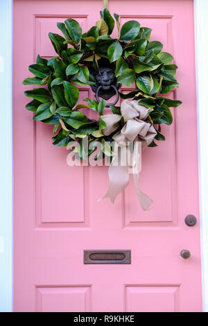 Traditionelle Magnolia Weihnachten Kranz ziert das rosa Holztür in das Dr Peter Fayssoux House Historic Home während der Feiertage auf Tradd Straße in Charleston, South Carolina. Fayssoux war der Surgeon General der Kontinentalarmee während der Amerikanischen Revolution. Stockfoto