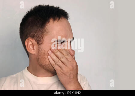 Schuß von Stattlichen frustrierten jungen Europäischen männlichen Schließen der Augen und Nase, Gefühl, weil der schlechte Geruch angewidert oder Gestank von verschwitzten Achseln oder d Stockfoto