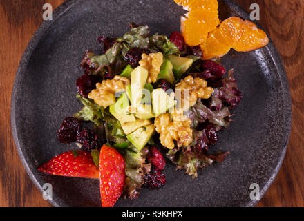 Grüner Salat mit Erdbeeren, Blackberry, Blutorangen, Alligator Pear, Rüben, Samen und Nüsse auf einer hölzernen Hintergrund, selektiver Fokus, den freien Speicherplatz. Del Stockfoto