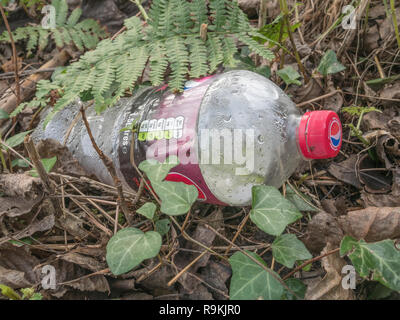 Leere PTFE-Kunststoff Soft drink Flasche in ländlichen Hecke graben verworfen. Metapher Kunststoff Verschmutzung, Umweltverschmutzung, Krieg auf Kunststoffabfälle. Stockfoto