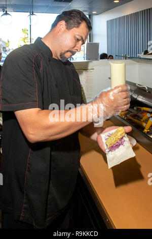 Mit einer Vielzahl von Zutaten, ein Hispanic Küchenchef kreiert eine Hand roll Snack in einem Japanischen Restaurant in Costa Mesa, CA. Stockfoto