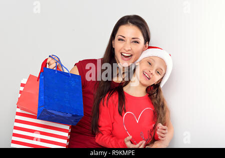 Glücklich lachend Mutter mit offenen Mund umarmen mit Liebe Ihr süsses freue mich Tochter in Santa Clause hat und Holding Weihnachtsgeschenk Pakete. Stockfoto