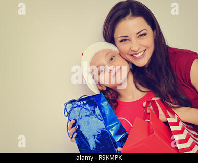 Glücklich lachend Mutter umarmte mit Liebe ihres süßen Tochter in Santa Clause hat und Holding Weihnachtsgeschenk Pakete. Getönte Farbe vintage Portrait Stockfoto