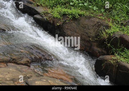 Wasser, das auf einem Hügel sehr schnell während eines Hochwassers in Südindien. Beginn eines Wasserfalls. Stockfoto