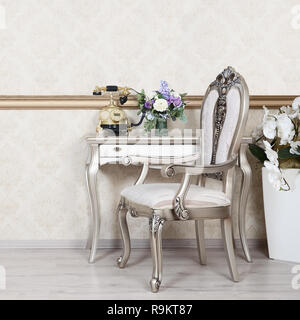 Ein Fragment eines retro Interieur mit einem Sessel und einen Schreibtisch, auf dem ein Telefon und eine Vase mit Blumen befindet. Stockfoto