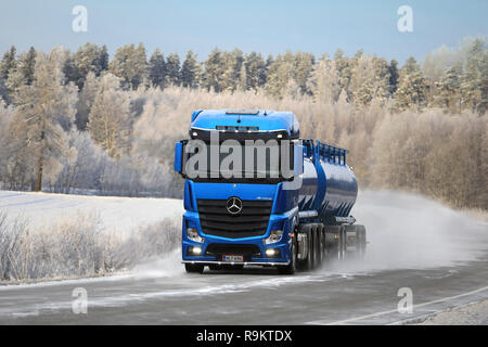 Blaue Mercedes-Benz Actros tank-Lkw der Kuljetusliike Markus Hanninen liefert Last auf verschneiten Autobahn durch die schöne Winterlandschaft in Salo, Finla Stockfoto